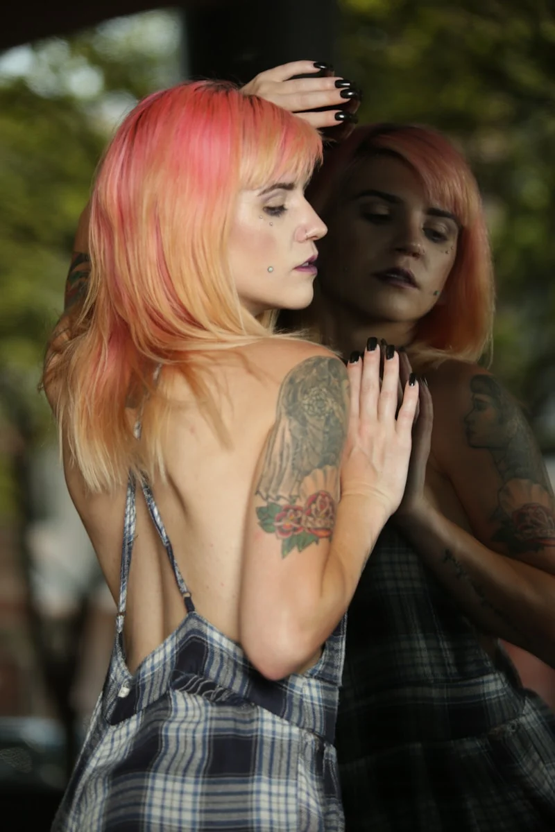 a woman with pink hair standing next to another woman
