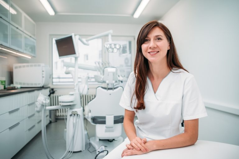 portrait,of,a,sincerely,smiling,young,female,dentist,dressed,in