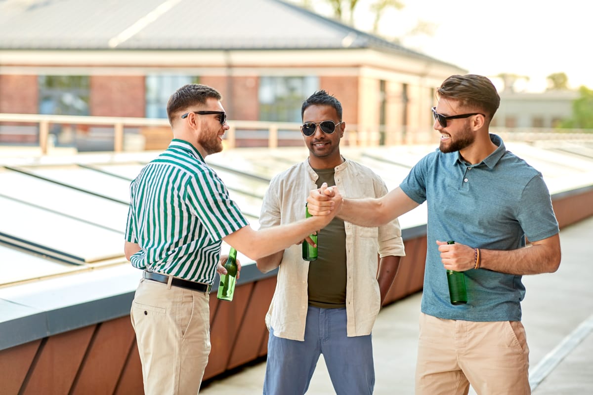 happy male friends drinking beer rooftop party