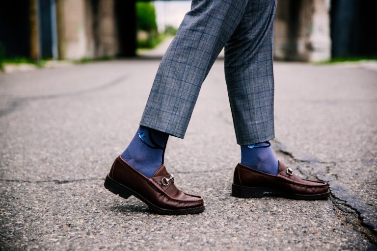 selective closeup shot of a person wearing blue pants and brown shoes with blue socks