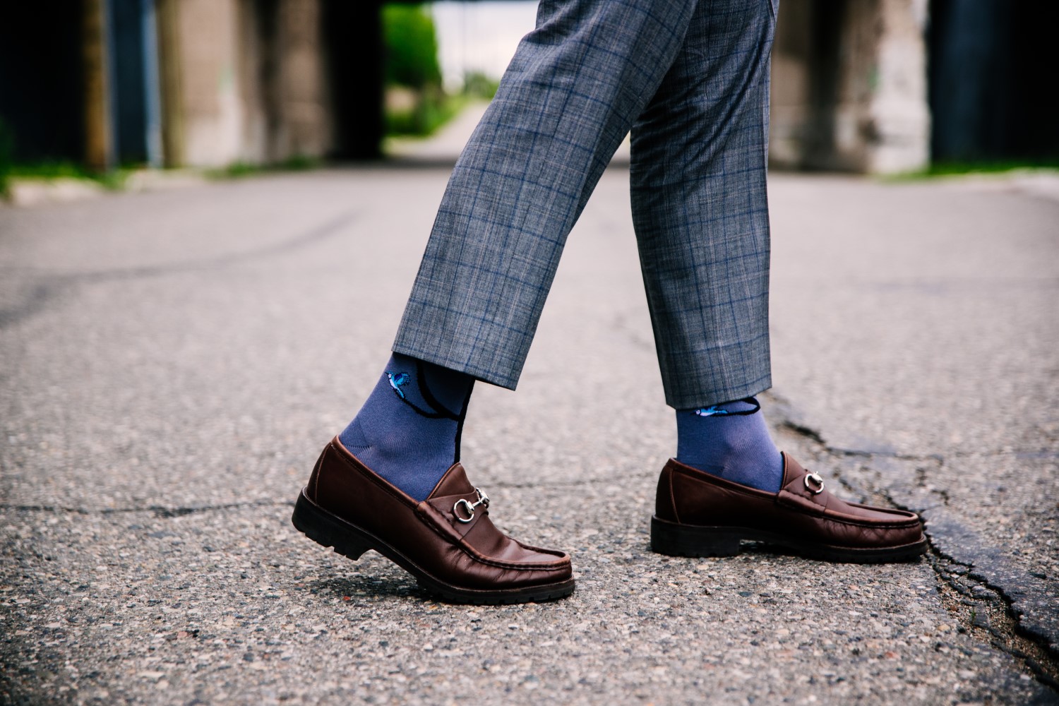 selective closeup shot of a person wearing blue pants and brown shoes with blue socks